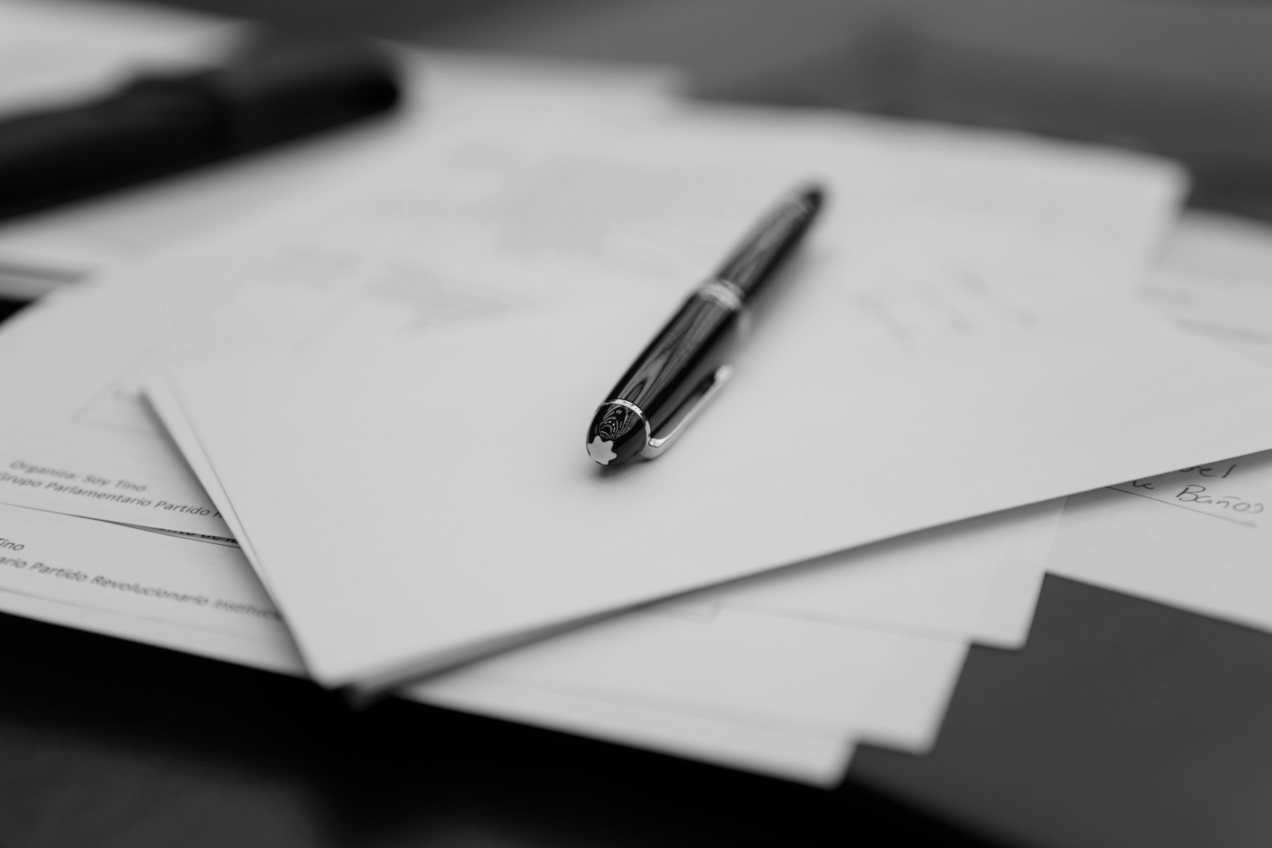 A fountain pen resting on a stack of signed documents