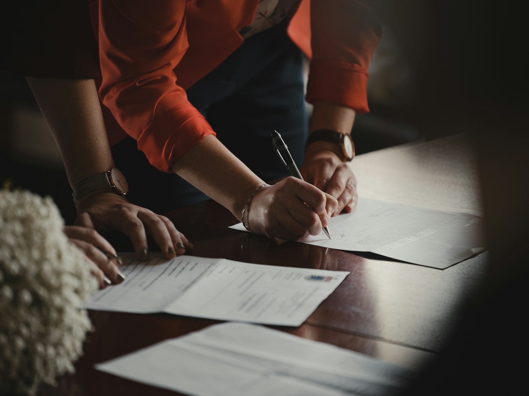 Two people signing documents at a timber table